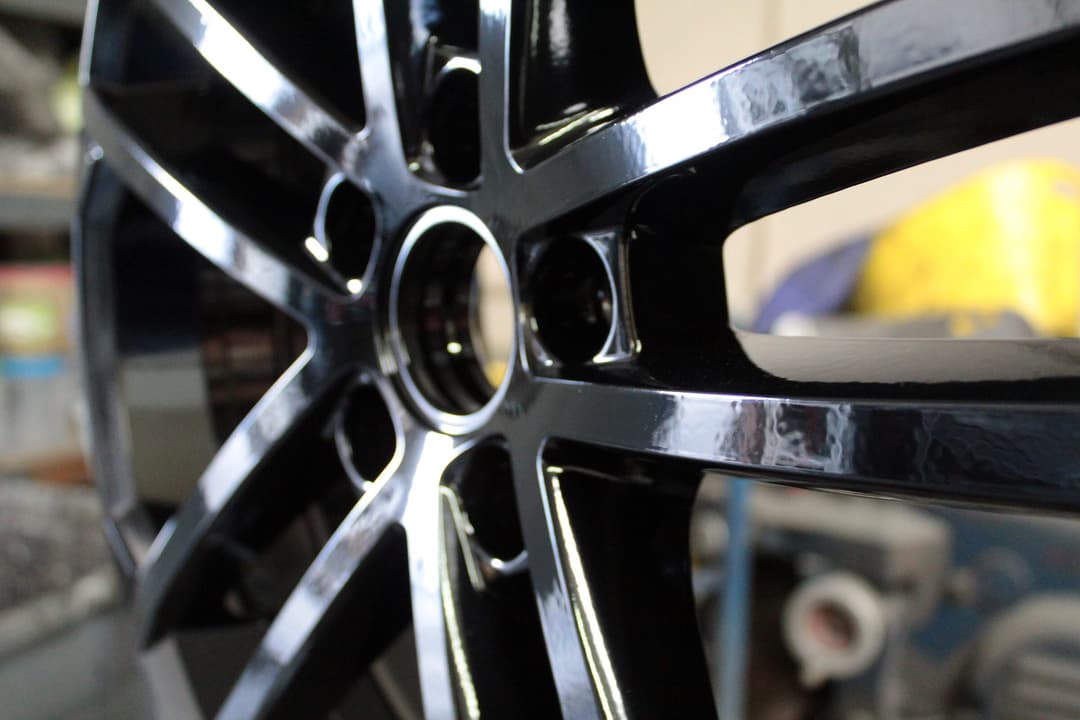 Close-up of a gloss black powder-coated wheel with a mirror shine