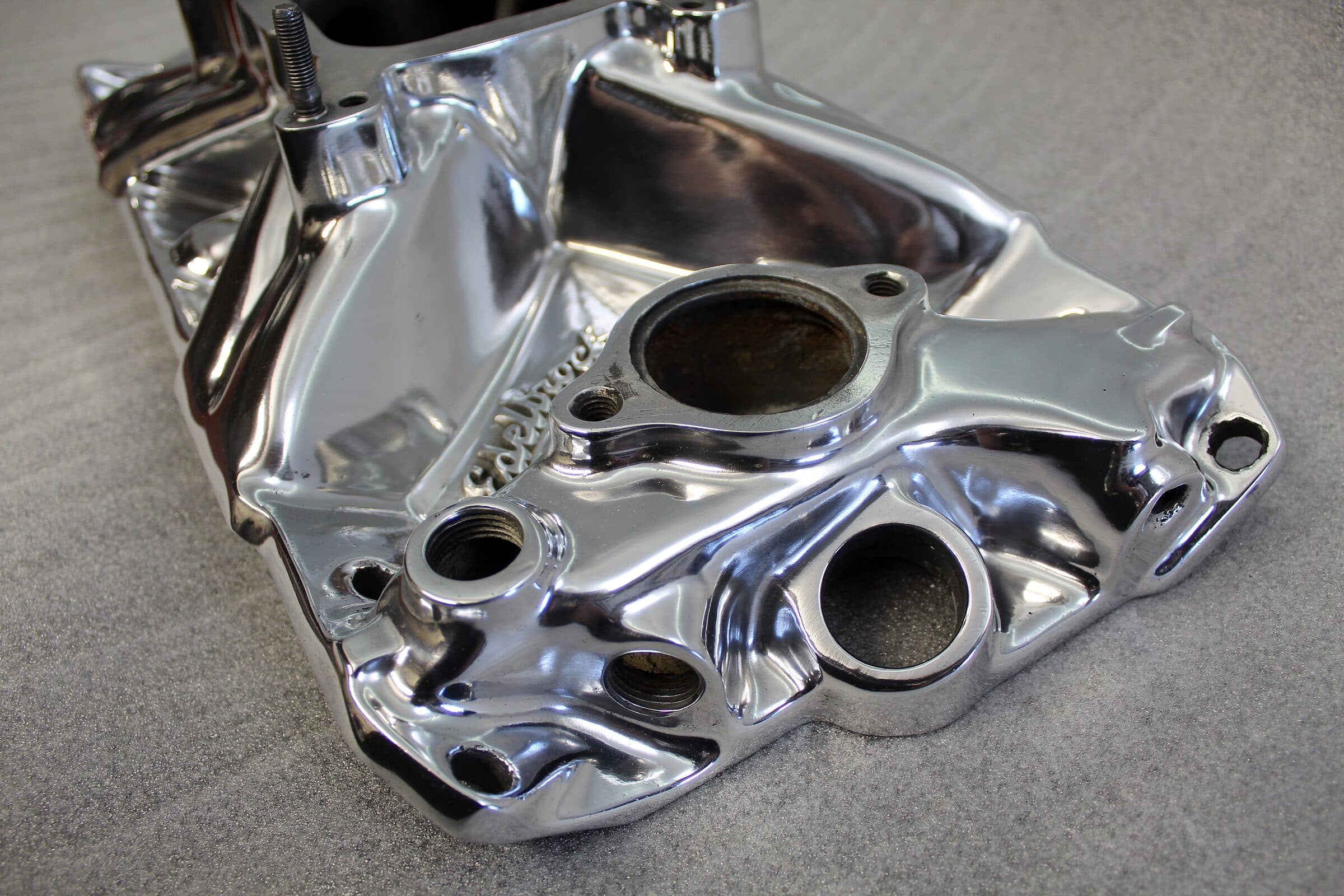 Mirror-polished aluminum intake manifold reflecting the shop lights