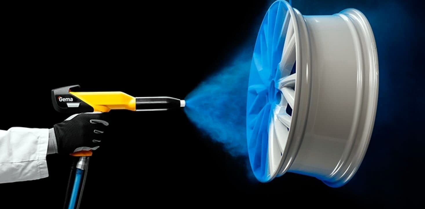 Electrostatic spray gun applying blue powder to a wheel