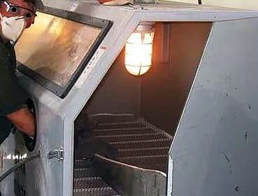 Part being sandblasted in a blast cabinet
